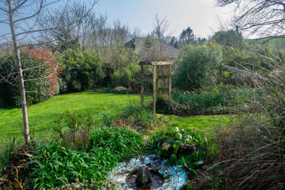 Beautiful gardens surround the property Lush garden with greenery, a gazebo, and a small pond surrounded by flowers.